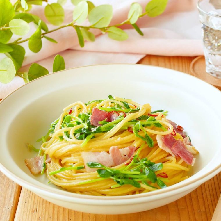 白い皿に盛り付けた豆苗とベーコンのパスタ