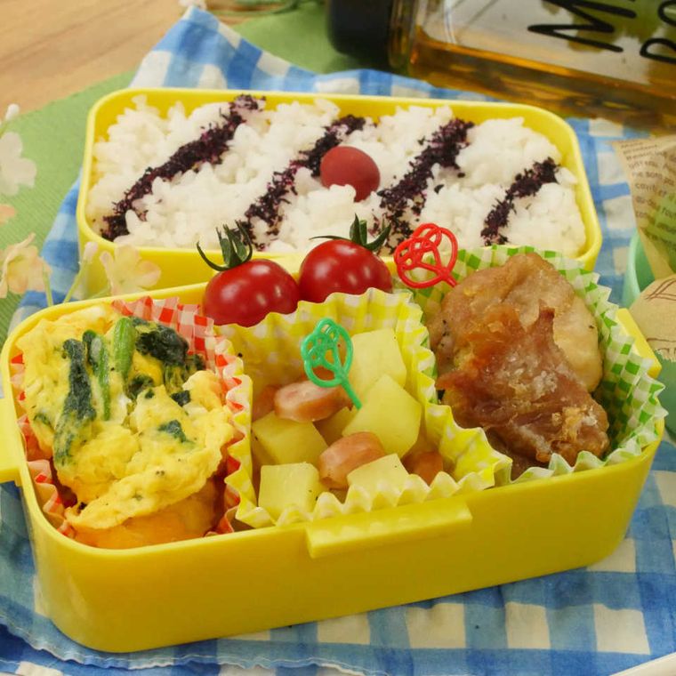 黄色い弁当箱に詰められている唐揚げ、ごはん、ジャーマンポテト