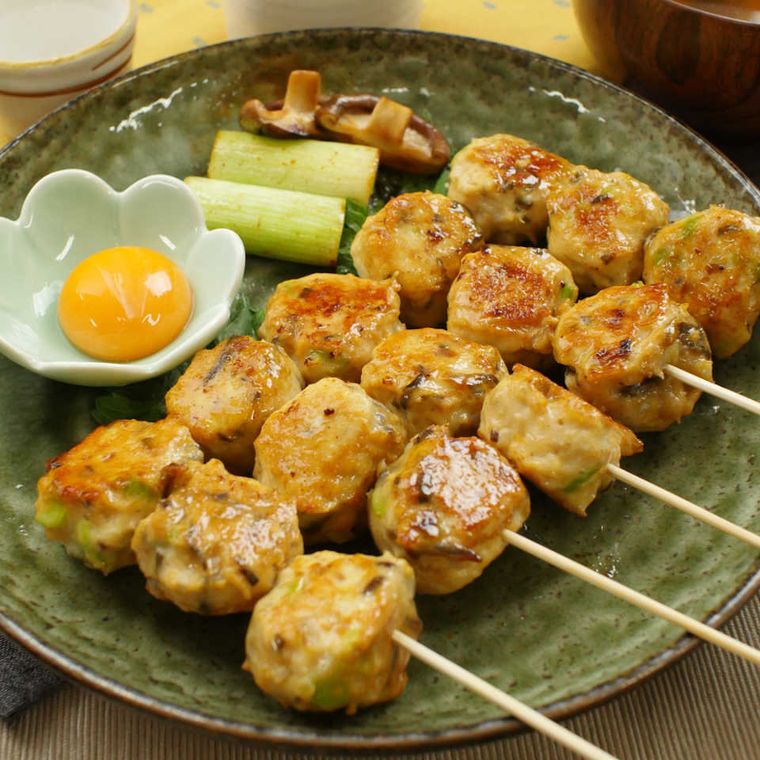 緑色の丸皿に並べた、串に刺した塩こんぶつくね