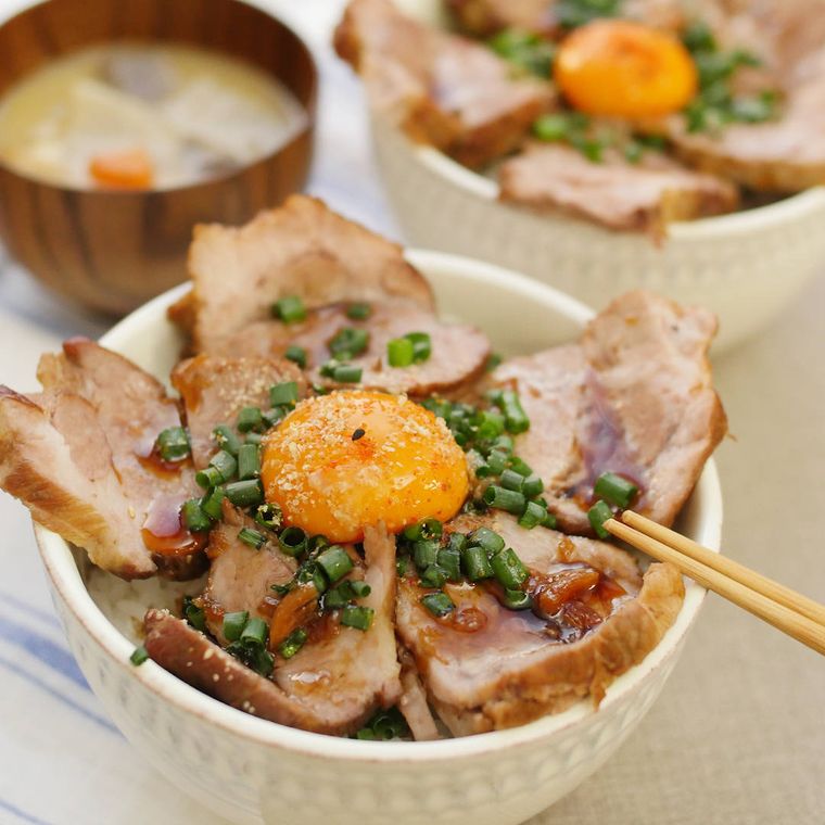 白い丼にごはんと一緒に盛り付けられているジューシー煮豚