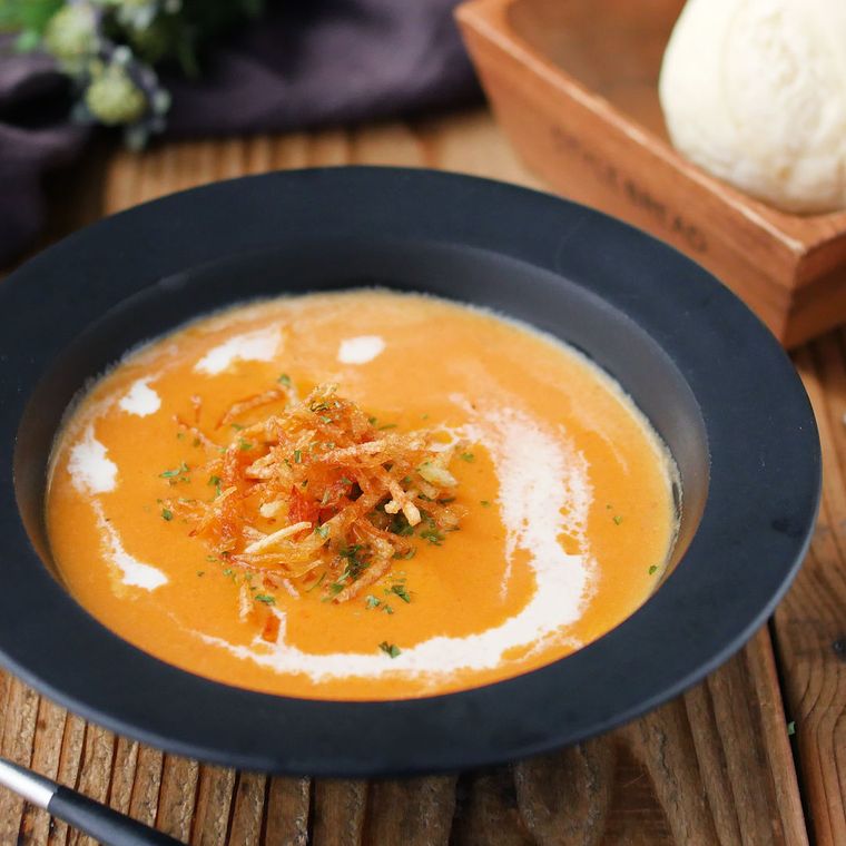 黒い皿に盛られたじゃがいもとにんじんのクリームスープ