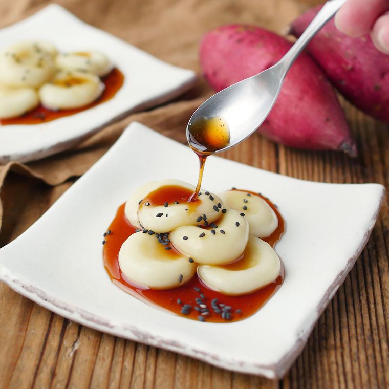 角皿にのせた白玉団子の大学芋にみたらしあんをかけている様子