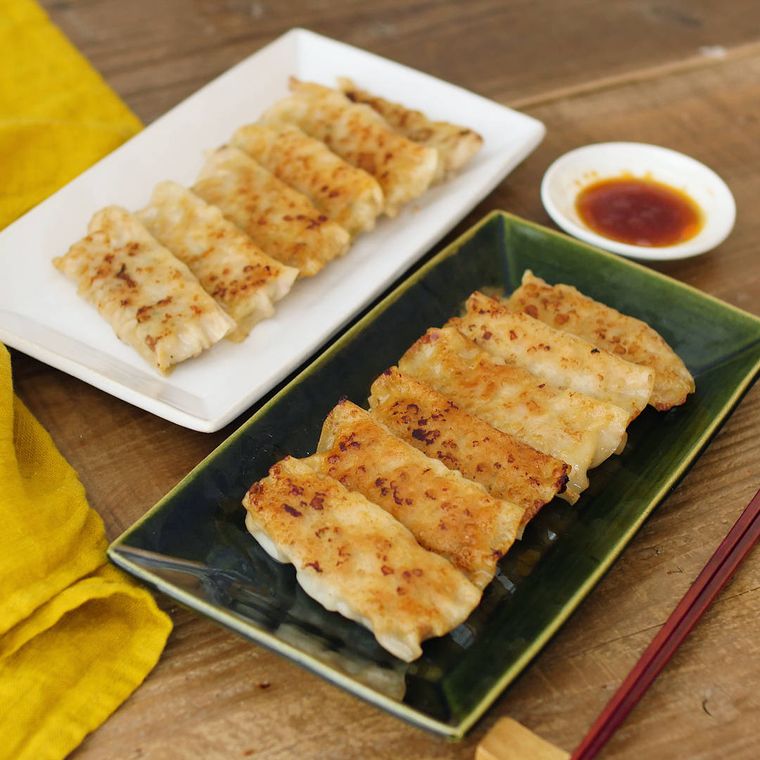 白と深緑色の長皿に盛りつけられた、豚ひき肉ともやし入りの棒餃子