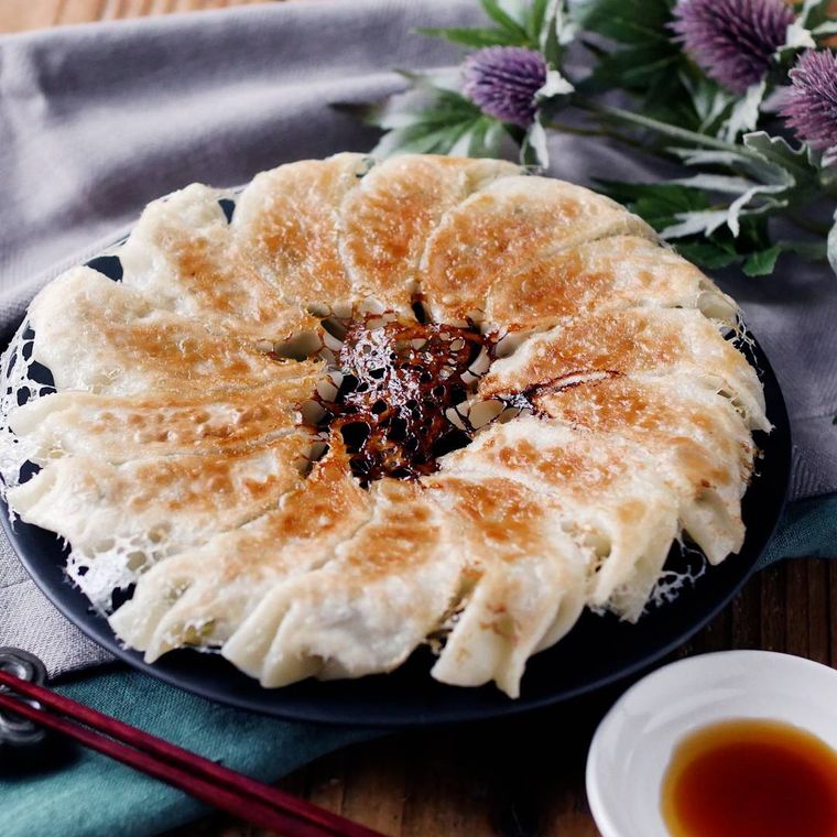 黒い皿に盛りつけられた豚ひき肉とキャベツ、こんにゃくの焼き餃子