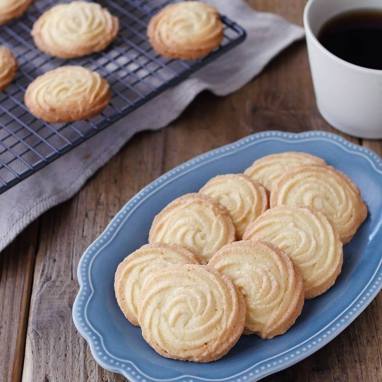 ケーキクーラーと縁取りのある皿に並んでいる絞り出しクッキー