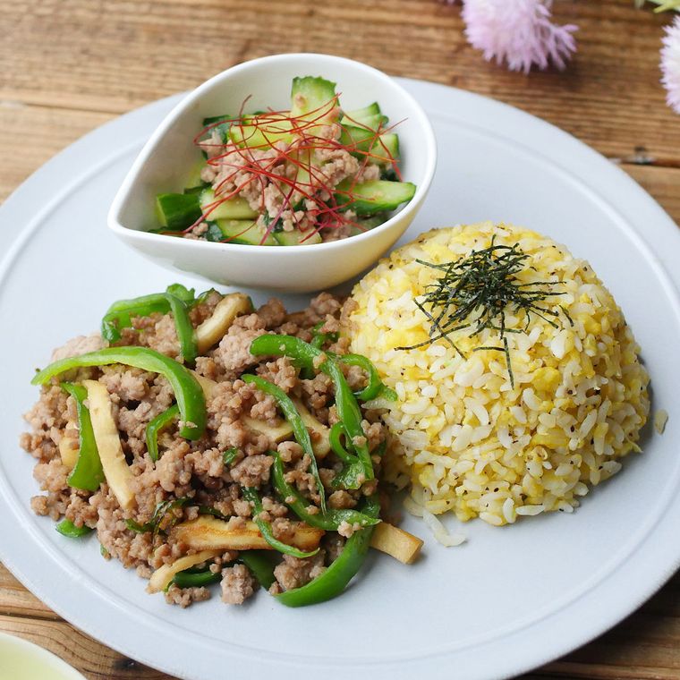 チャーハン、青椒肉絲風炒め、きゅうりの肉みそ和えを盛り付けた白い丸皿