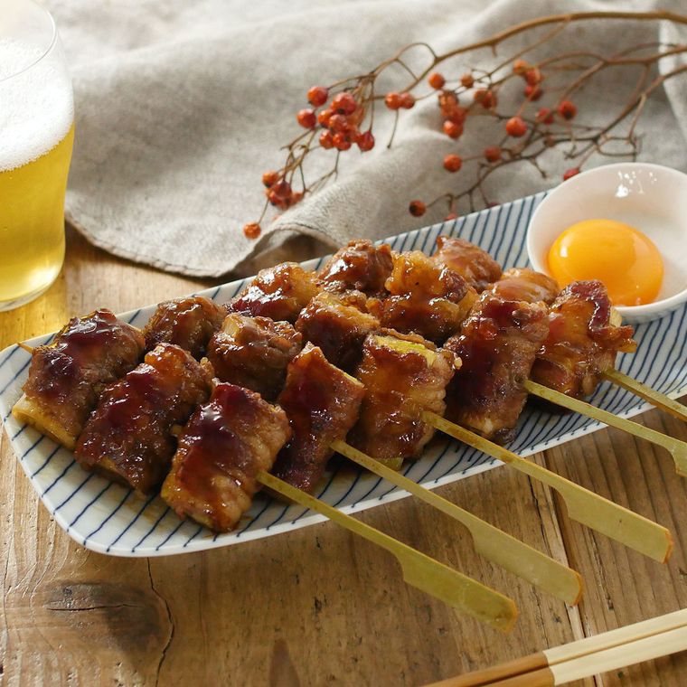 青い模様入りの白い皿に盛られた、長ねぎのすき焼き巻き