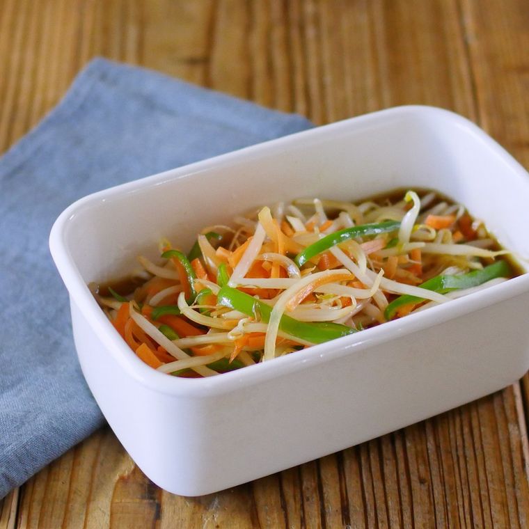 白い保存容器に入ったもやし、にんじん、ピーマンなどの南蛮漬け