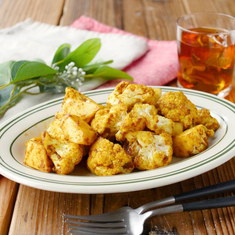 ライン入りの皿に盛られているカリフラワーのカレー粉炒め