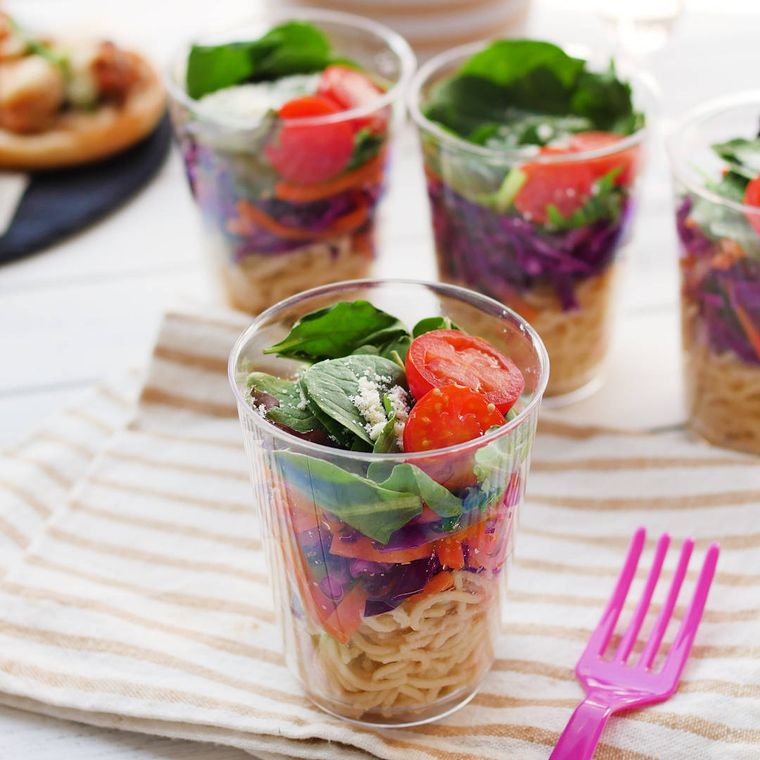 透明なカップに盛りナプキンの上にのせた、カップパスタサラダ