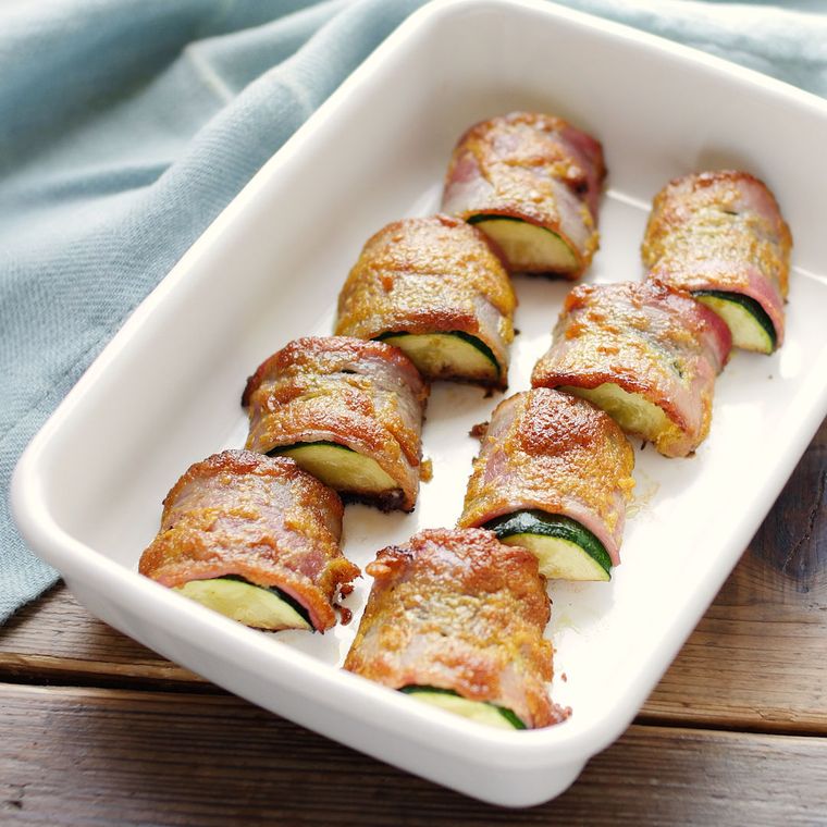 白い保存容器に並べられたズッキーニのベーコン巻き