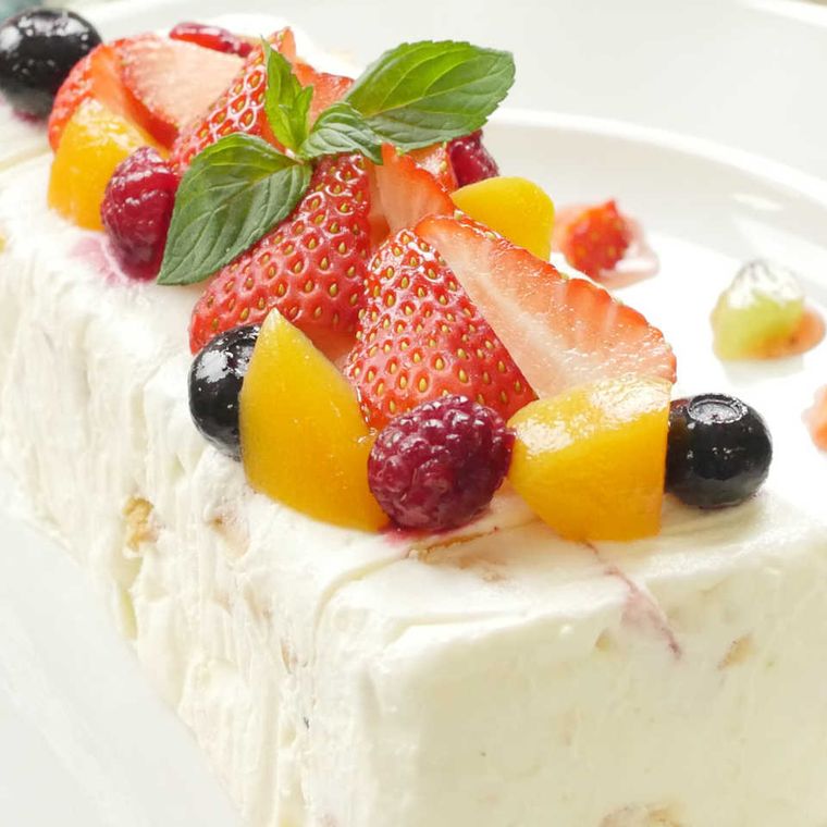 フルーツたっぷりのセミフレッドアイスケーキが型から出され白い皿に盛り付けられているところ