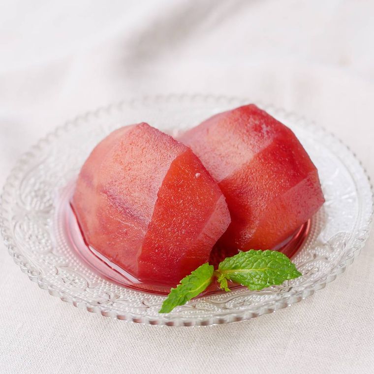 シナモンと赤ワインで煮詰めたりんごのコンポートがガラスの円形のプレートに盛り付けられているところ