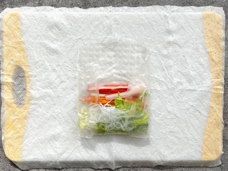 ライスペーパーでカニカマ、にんじん、レタスなどを巻いている様子