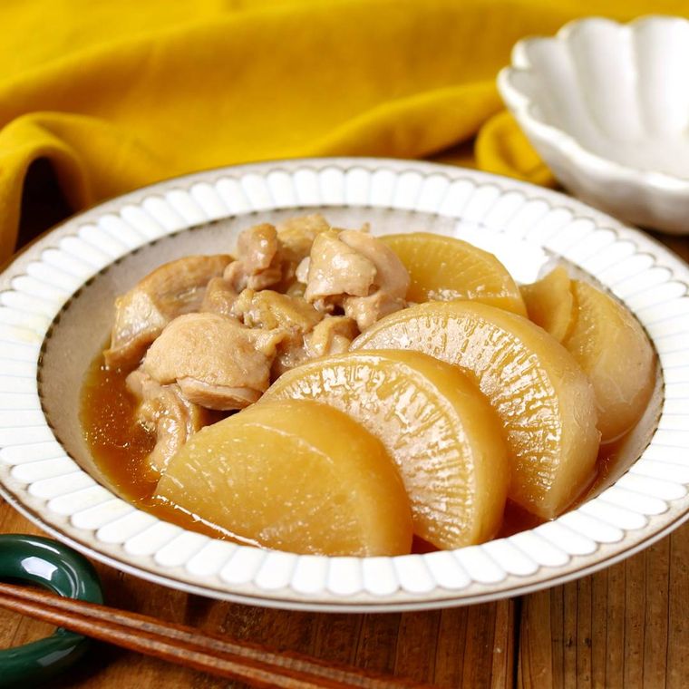 白い皿に盛られている鶏もも肉と大根の煮物