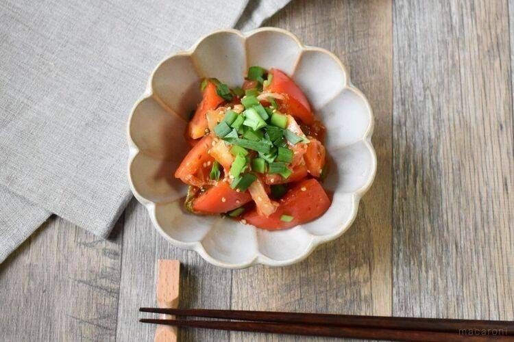 テーブルの上、トマトのキムチ和えが盛られた器、お箸が並んでいる