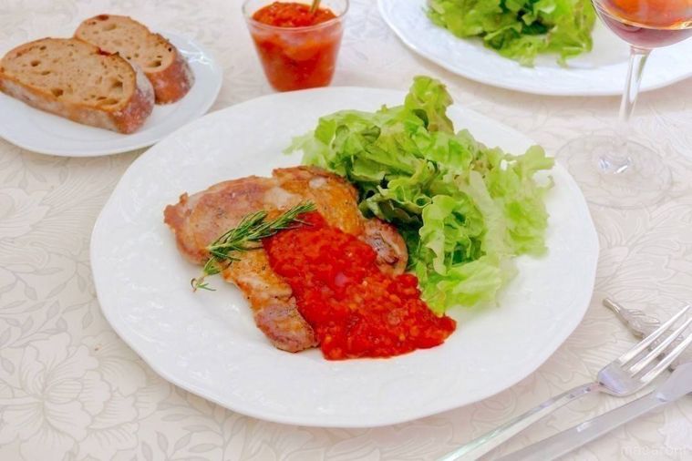 白い丸プレートに盛り付けた鶏肉ソテーのトマトソースがけ