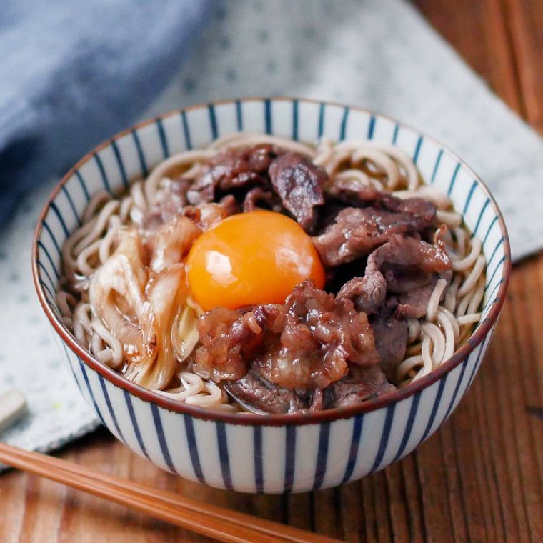 青の縞模様のどんぶりに入ったすき焼き風牛肉そば