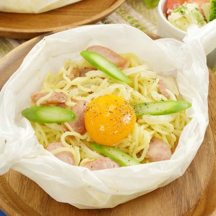 包み紙のまま食卓に出されている包み焼きしたカルボナーラ風焼きそば