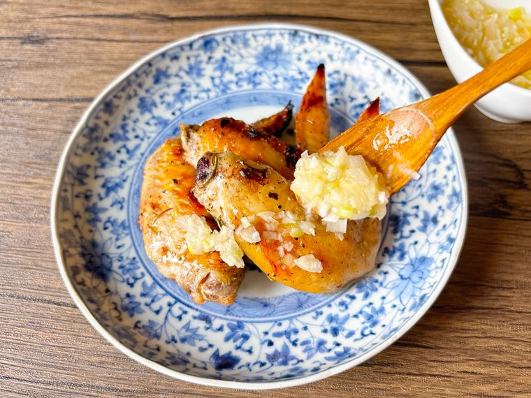 和皿に盛られた鶏手羽先のねぎ塩だれのせ