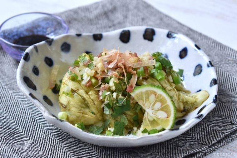 薬味をのせて器に盛りつけた焼きなす、奥にしょうゆ皿