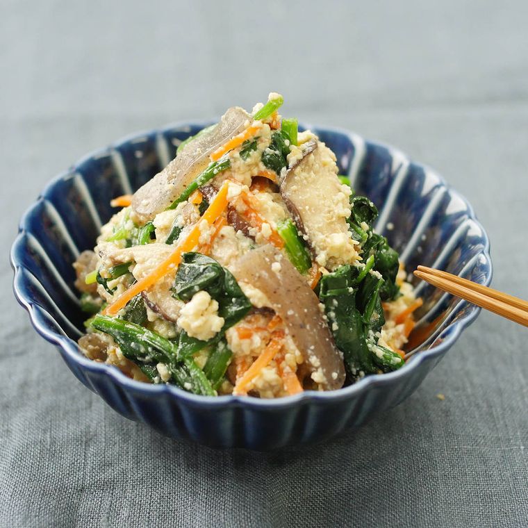 青い皿に盛り付けた豆腐とこんにゃく、にんじん、ほうれん草の白和え