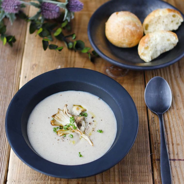 藍色の皿に盛りつけられているきのことれんこんのポタージュ