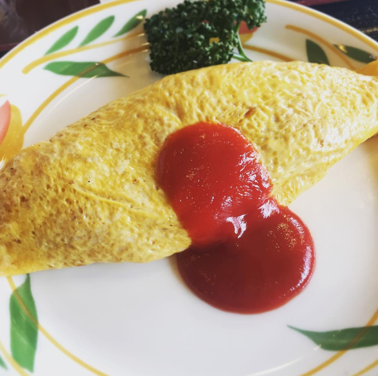 枝が描かれた丸いお皿に盛り付けられたシンプルなオムライス