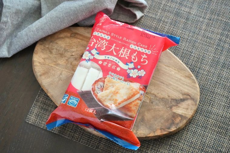 茶色いランチョンマットと木のカッティングボードと赤いパッケージの業務スーパーの台湾大根もち