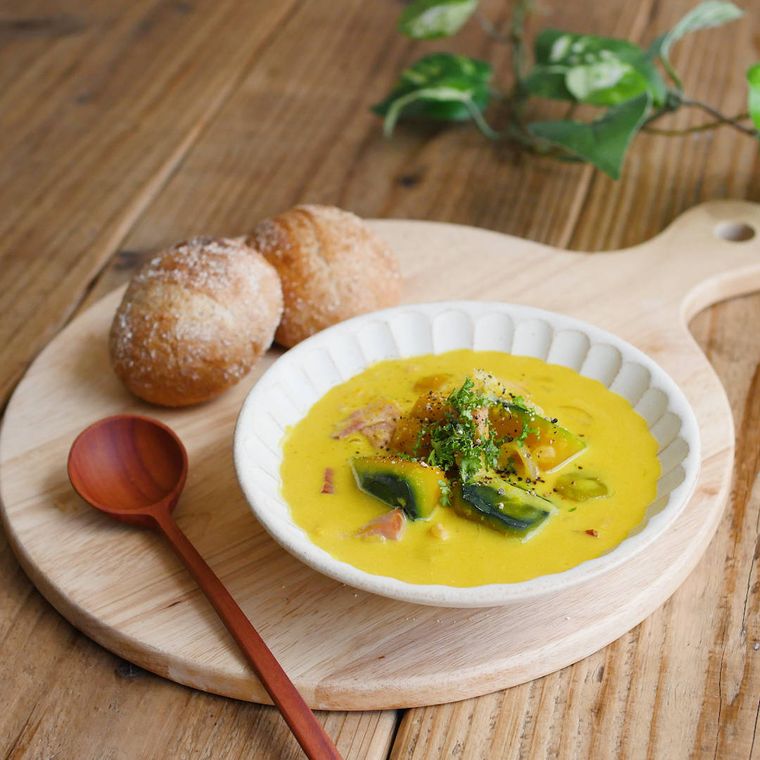 角切りかぼちゃがゴロゴロ入ったスープとパンをのせたカッティングボード