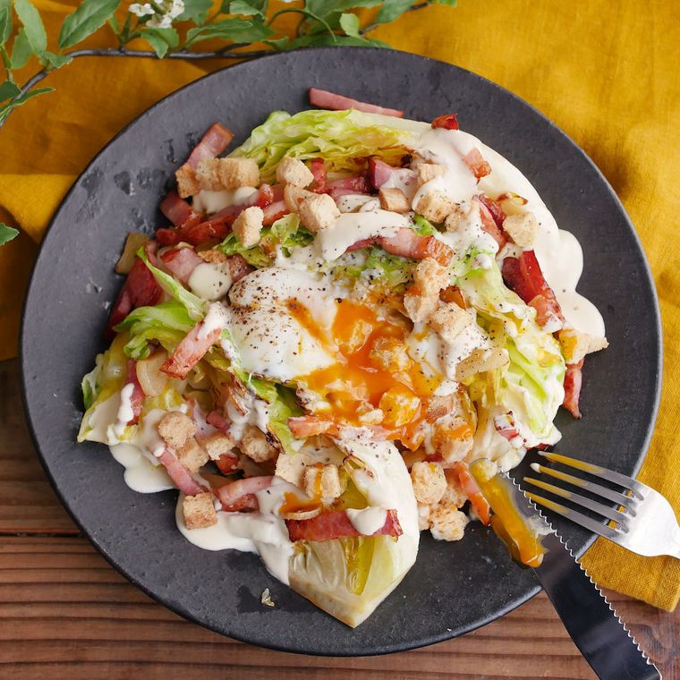 黒い丸皿に盛った焼きキャベツのシーザーサラダ