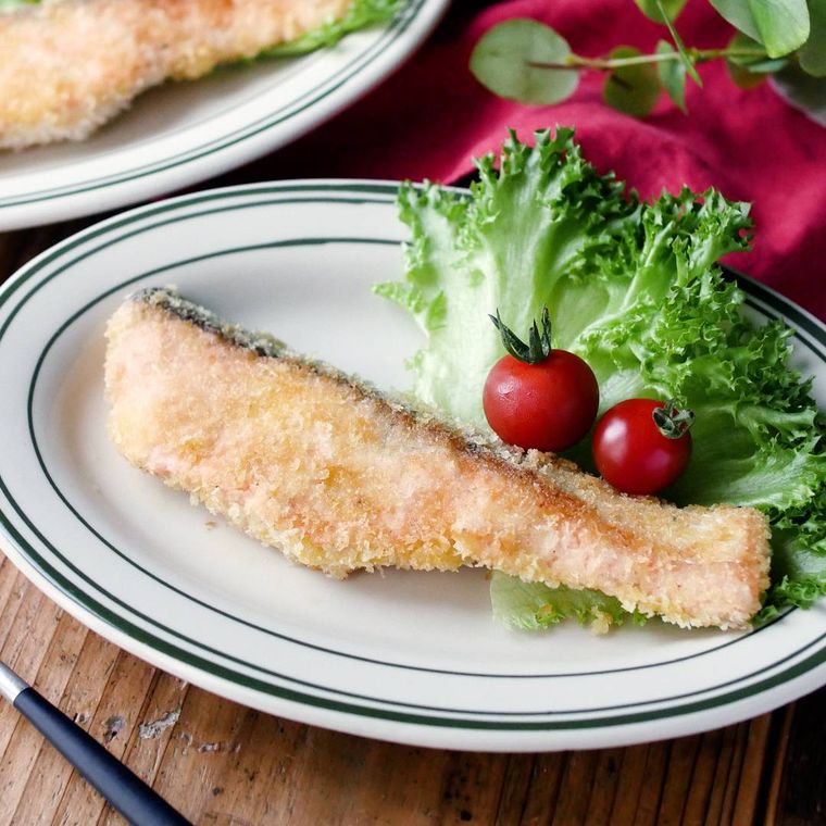 ライン入りの皿に盛られているサケのマヨパン粉焼き
