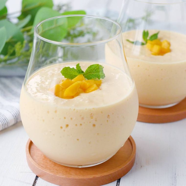 透明なグラスに入ったマンゴースムージ、冷凍マンゴーとミントトッピング