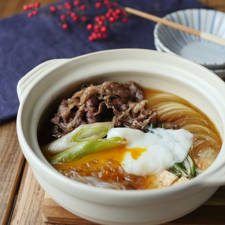 白い土鍋に入っている牛肉やしらたき、豆腐などのすき煮