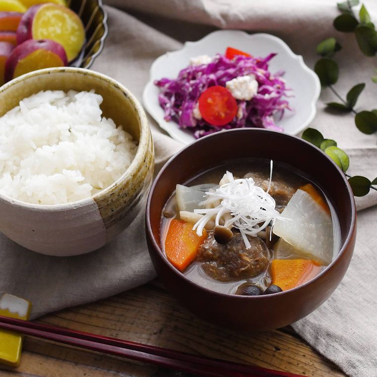赤茶色のお椀に盛りつけられたつみれ汁と茶碗入りのごはん
