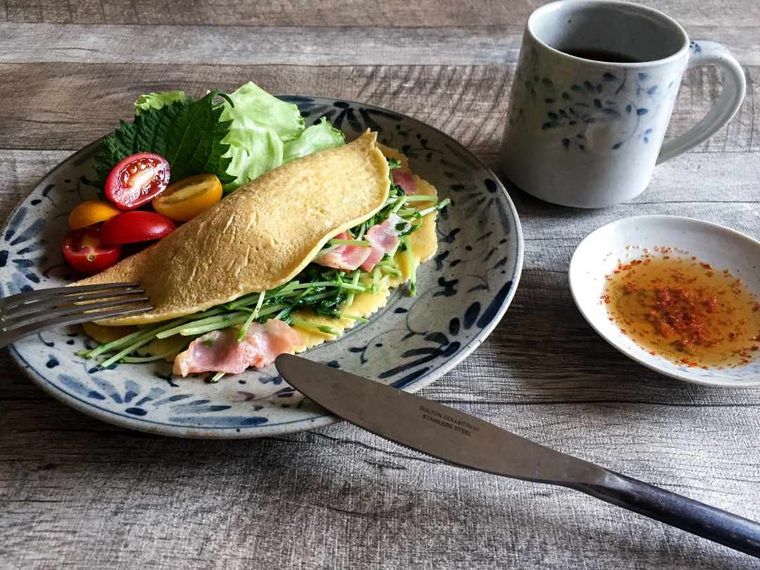 丸皿に盛り付けた豆苗のバインセオや小皿に入ったたれが並ぶテーブル