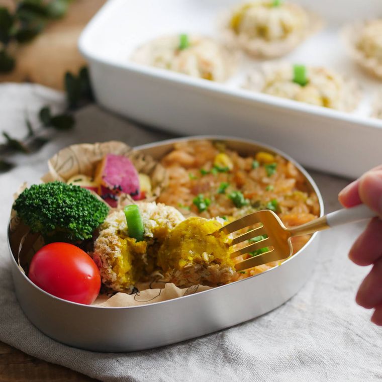 シルバーのお弁当箱に入ったミニかぼちゃコロッケと味付きごはん、数種類のおかず