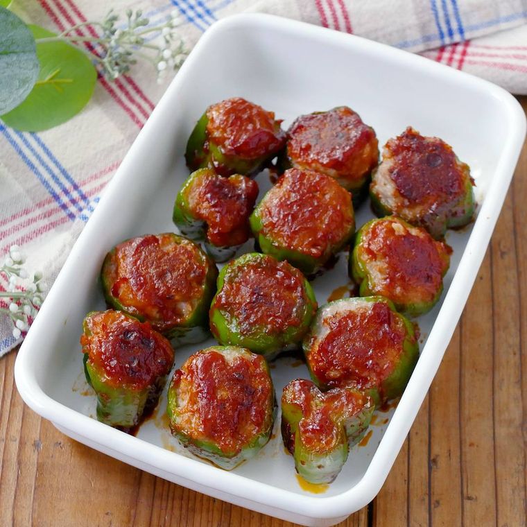 白いホーローの保存バッドに盛りつけられた輪切りピーマンの肉詰め