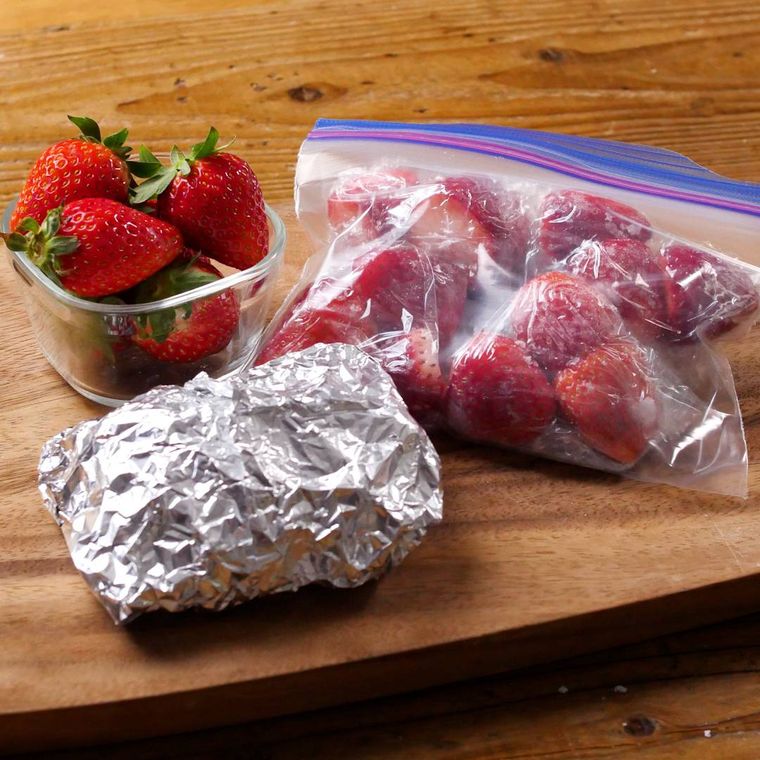 木のボードにおかれたジッパー付き保存袋に入ったいちご、アルミホイルで包んだいちご、器に盛られたいちご