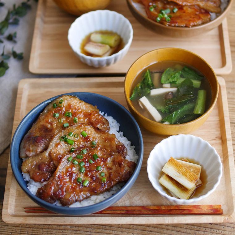 四角い盆に並べられたガリバタ豚丼、みそ汁や長ねぎのマリネ