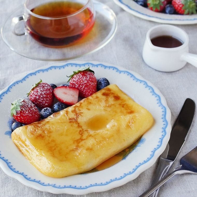 餅のフレンチトーストといちごとブルーベリーが盛り付けられている皿と、ガラスのカップに入った茶色い飲み物