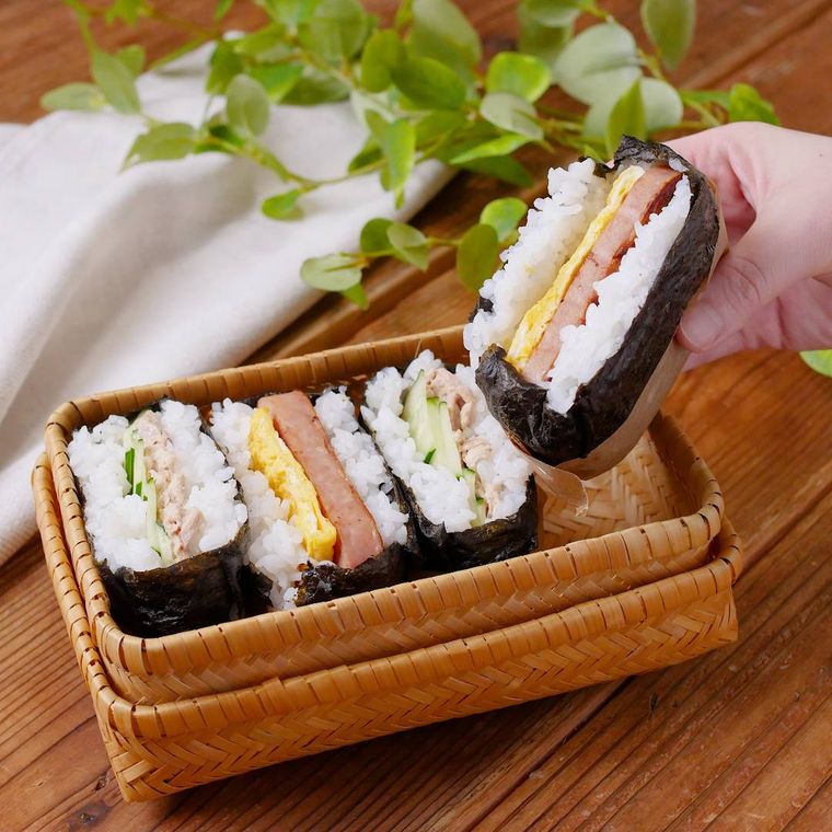 かごの弁当箱に入った折りたたみおにぎらず