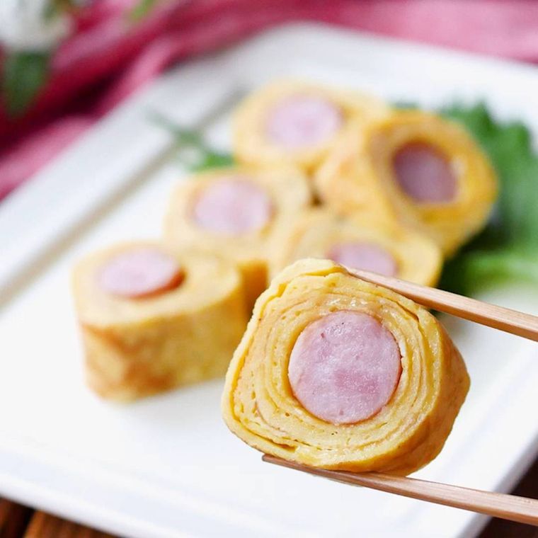 ウインナーの洋風卵焼きを箸でつかんでいる