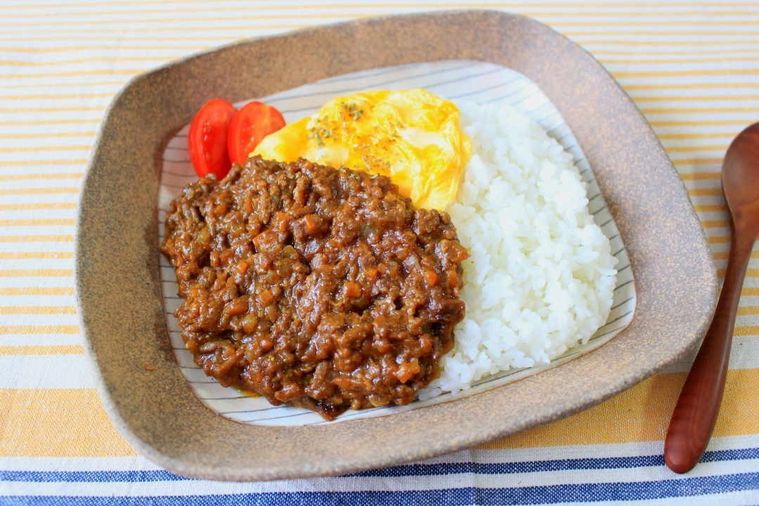 縁が茶色のカレー皿に盛られたキーマカレーと卵トッピング