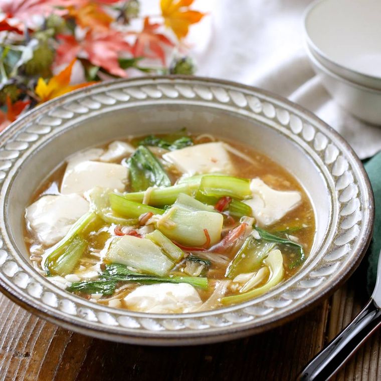 縁取りのある皿に盛りつけられた豆腐とチンゲン菜、カニかまの旨煮