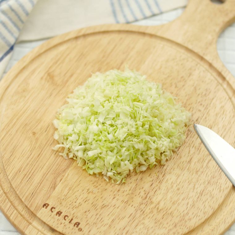 丸いカッティングボードの上でみじん切りにされたキャベツ