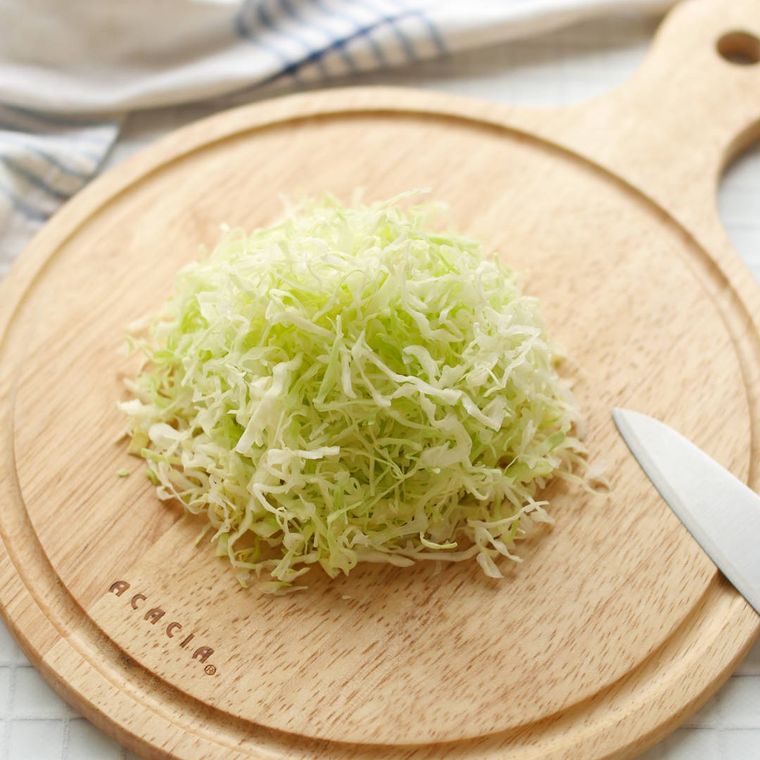 丸いカッティングボードの上で千切りにされたキャベツ