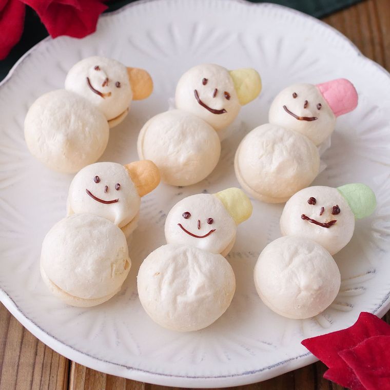 白い皿に並べたスノーマンのメレンゲクッキー