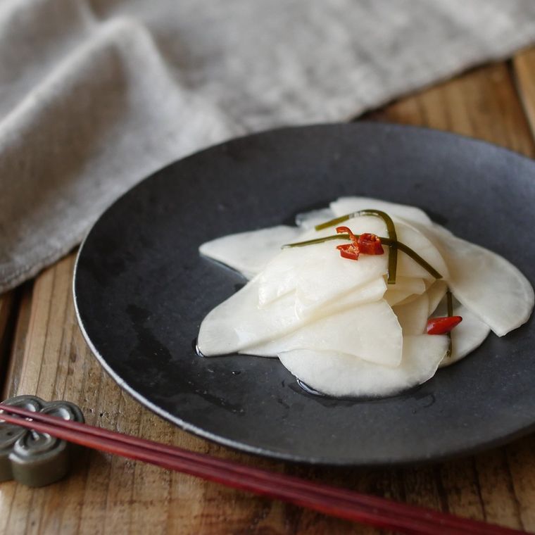 濃いグレー色のマットな小皿に盛りつけられたかぶの千枚漬け