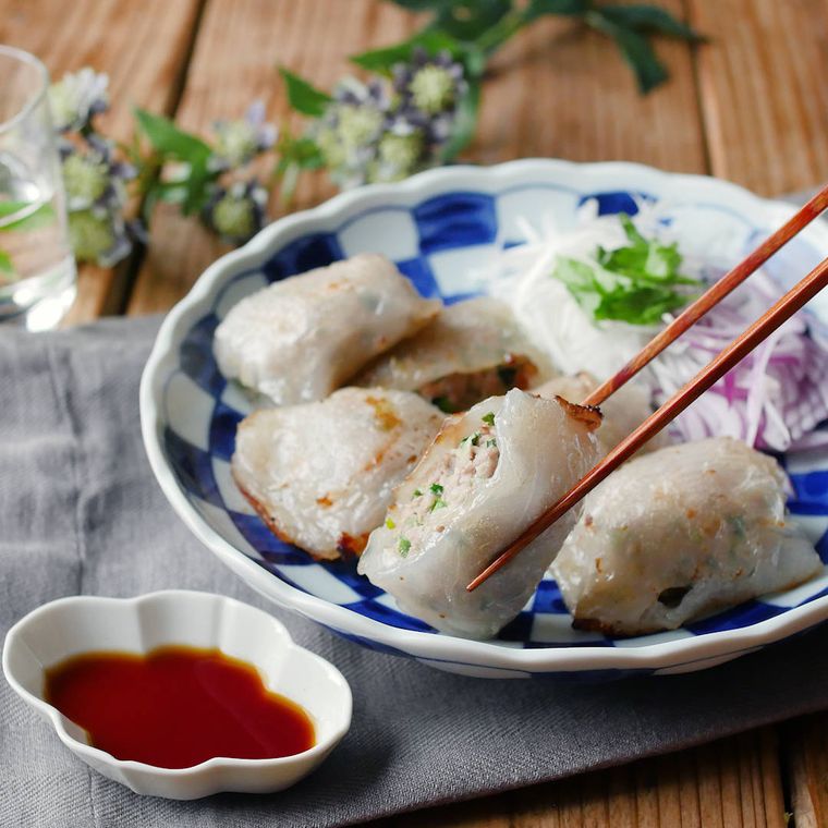 皿に盛られたライスペーパーで簡単ニラ饅頭を箸でつまんでいる様子